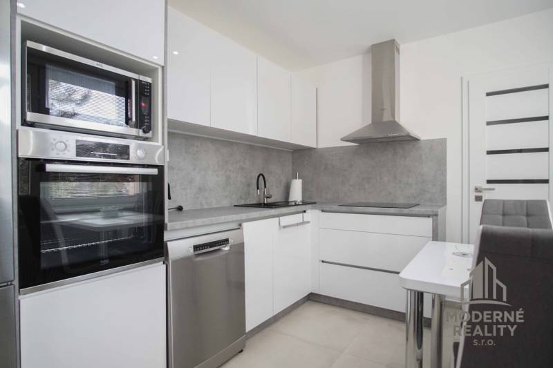 Küche in einer 2-Zimmer-Wohnung mit eingebauten Geräten und Essecke.