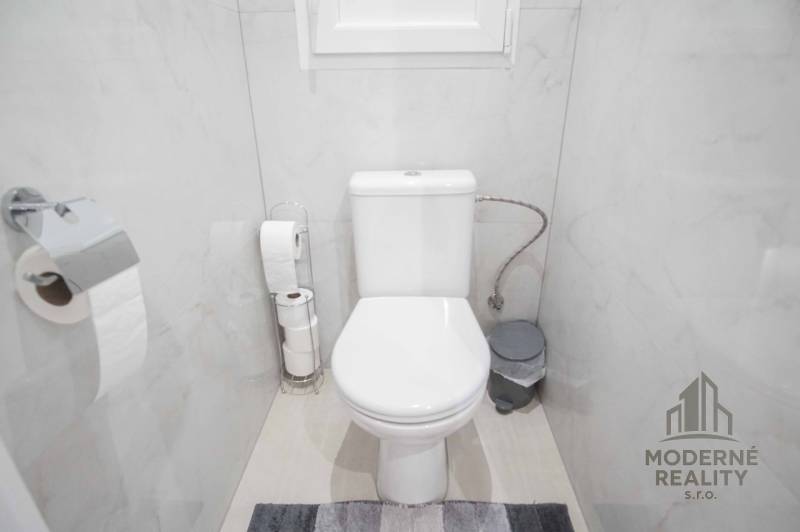 Badezimmer mit Toilette in einer 2-Zimmer-Wohnung, helle Fliesen und Accessoires in neutralen Farben.