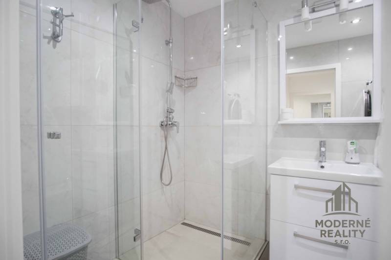 Badezimmer mit Dusche und Waschbecken in einer 2-Zimmer-Wohnung.