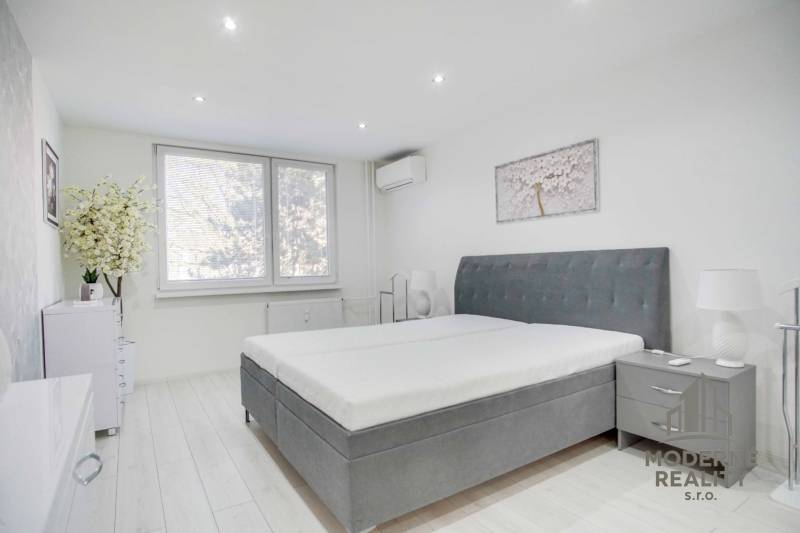 Schlafzimmer in einer 2-Zimmer-Wohnung mit großem Bett und Dekoration in gedämpften Farben.