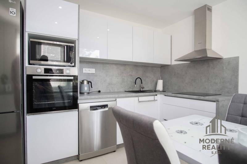 Küchenbereich einer 2-Zimmer-Wohnung mit weißen Schränken und grauer Arbeitsplatte.