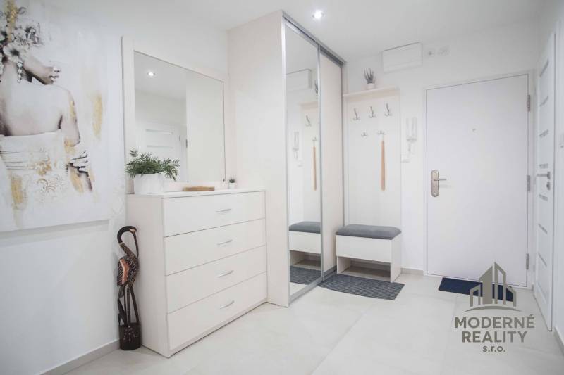 Eingangsflur mit weißen Möbeln und Spiegel in einer Zweizimmerwohnung.