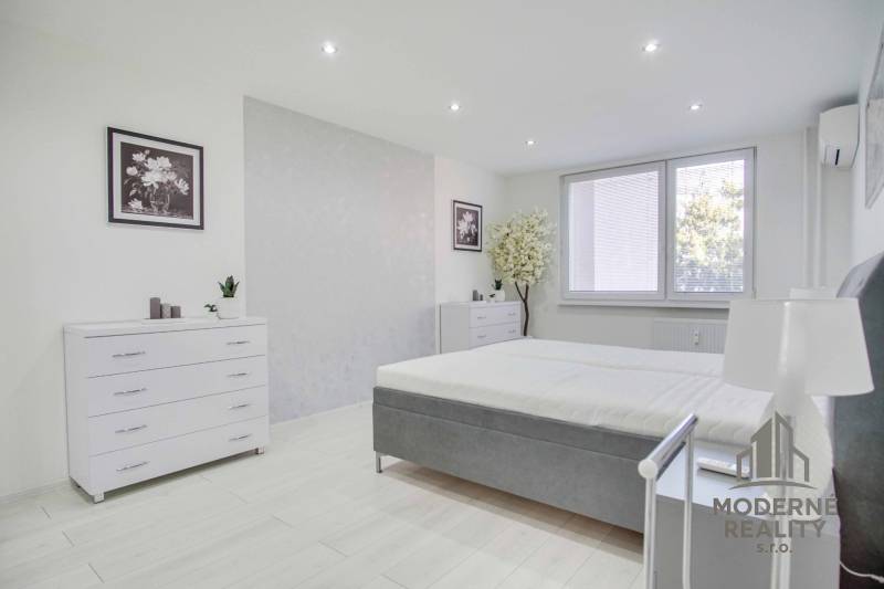 Helles Schlafzimmer in einer Zweizimmerwohnung mit weißen Möbeln und Dekorationen.