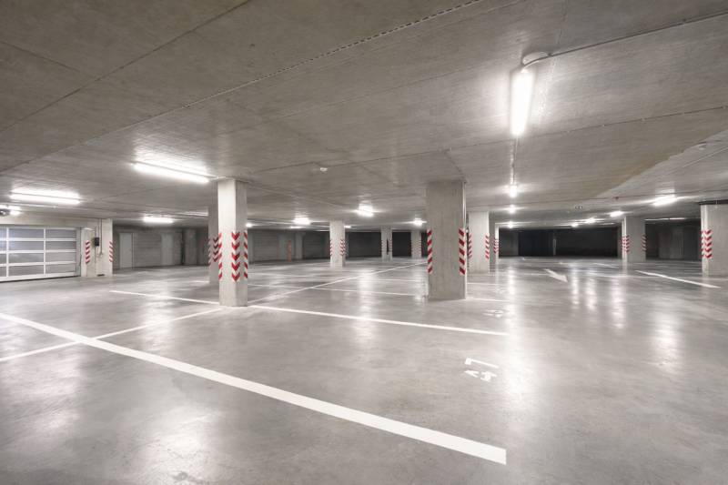 Geräumige Garagen mit markierten Parkplätzen, helle Beleuchtung, Betonpfeiler.