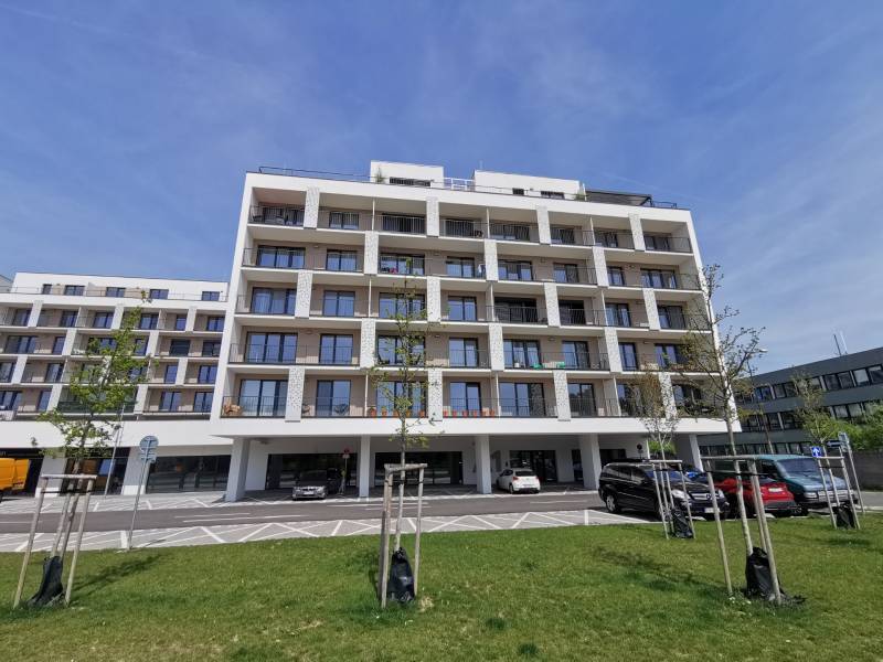 Wohnhaus in der Eduard-Wenzl-Straße mit Parkplätzen und Garagen im Vordergrund.