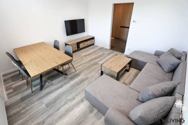 Wohnzimmer in einer 3-Zimmer-Wohnung mit Holzboden, Sofa und Fernseher.