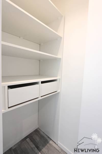 Weißer Kleiderschrank mit Schubladen und Regalen in einer 3-Zimmer-Wohnung.