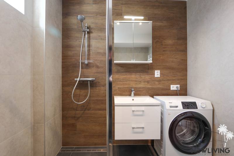 Badezimmer in einer 3-Zimmer-Wohnung mit Holzelementen und Waschmaschine.