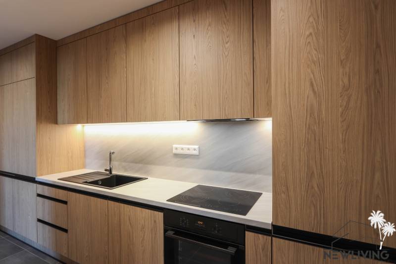 Küche in einer 3-Zimmer-Wohnung mit Holzelementen in der Küchenzeile und eingebauten Geräten.