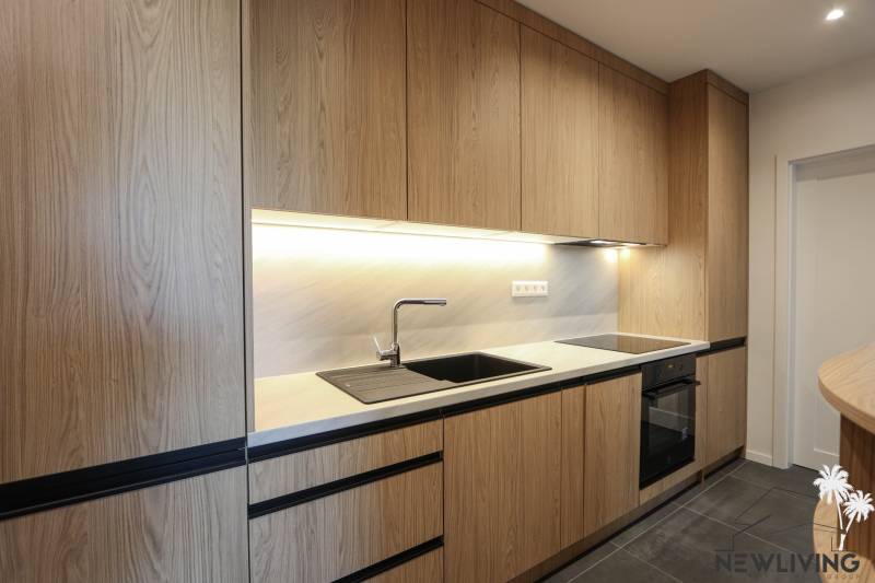 Küche mit Holzdekor, schwarzen Details, eingebauten Geräten in einer 3-Zimmer-Wohnung.