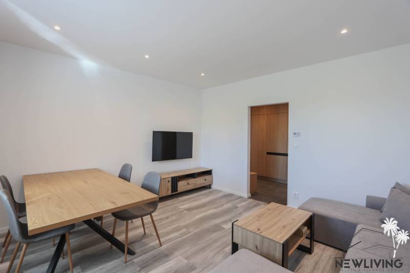 Wohnzimmer in einer 3-Zimmer-Wohnung mit Holzboden und Holzmöbeln.