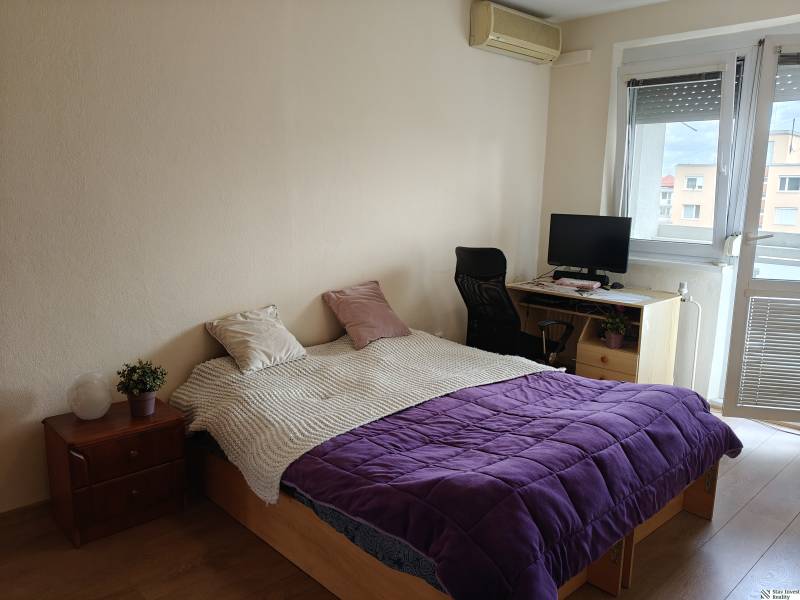 Schlafzimmer in einer 3-Zimmer-Wohnung mit Bett, Arbeitsecke und Boden mit Holzdekor.