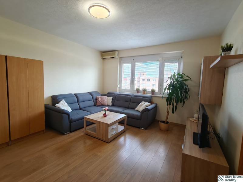 Wohnzimmer mit Ecksofa, Holzboden und Fernseher in einer 3-Zimmer-Wohnung.