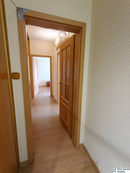 Ein Flur mit Türen und einem Boden in Holzoptik in einer 3-Zimmer-Wohnung.