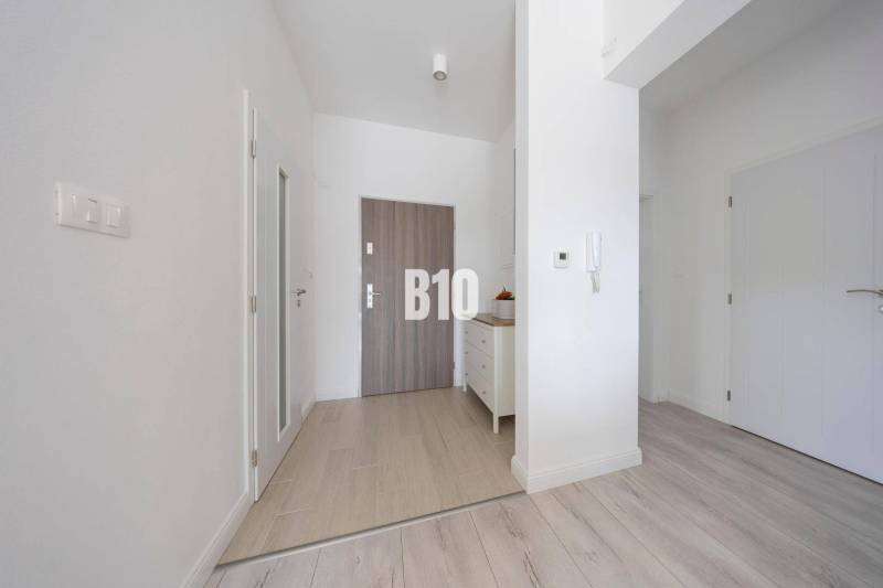 Eingangsflur mit weißen Wänden und einem Boden in Holzoptik in einer 3-Zimmer-Wohnung.