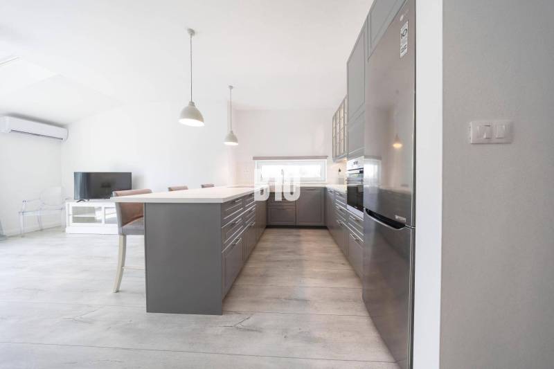 Küche in einer 3-Zimmer-Wohnung mit einem modernen Kühlschrank aus Stahl und einem Boden in Holzoptik.