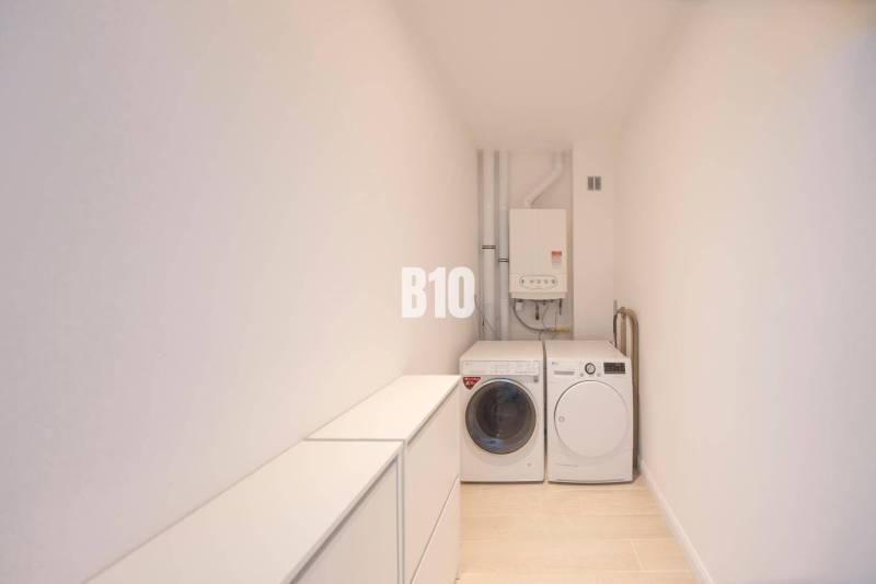 Waschmaschine, Trockner und Kessel im Waschraum einer 3-Zimmer-Wohnung mit Holzboden-Dekor.