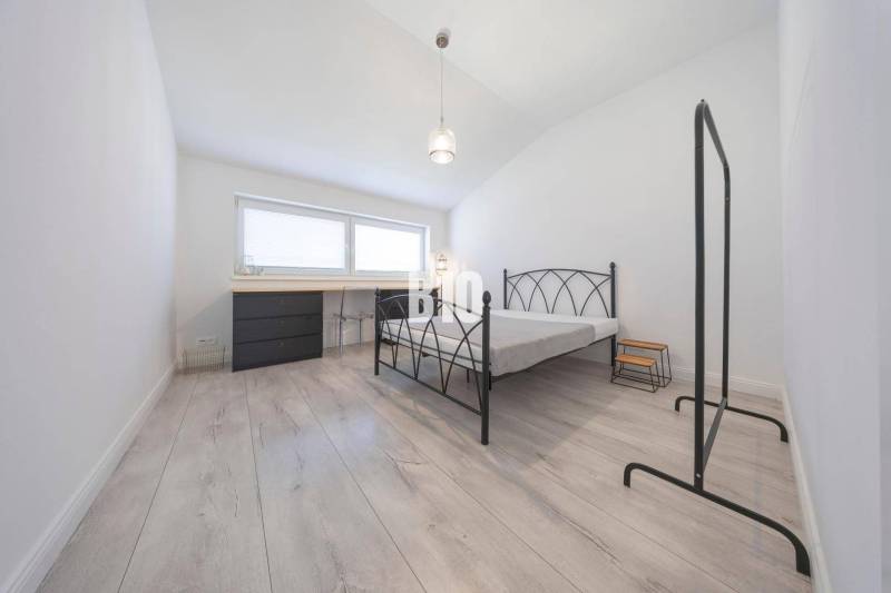 Ein Schlafzimmer mit einem Boden in Holzoptik und einem Bettgestell aus Metall in einer 3-Zimmer-Wohnung.