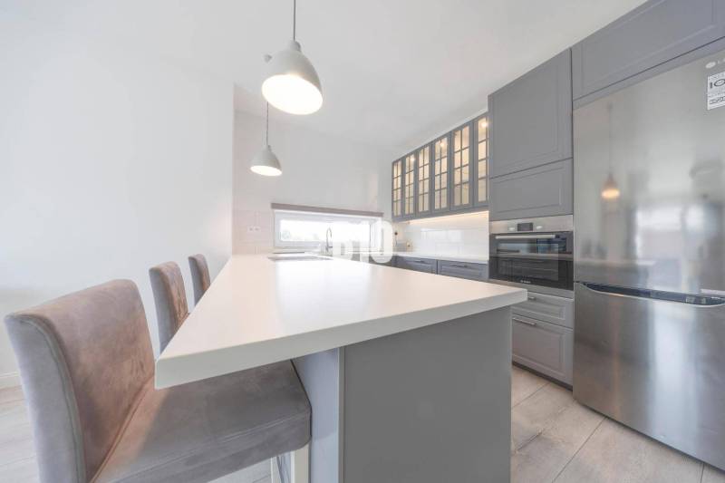 Küche in einer 3-Zimmer-Wohnung mit Insel, grauen Schränken und modernen Geräten.