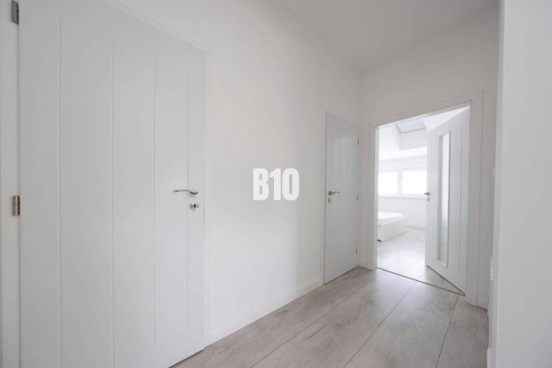 Ein heller Flur in einer 3-Zimmer-Wohnung mit einem Boden in Holzoptik und weißen Türen.