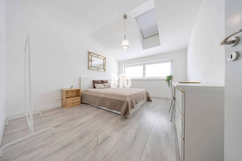Helles Schlafzimmer mit großem Bett, Fenster und Holzboden in einer 3-Zimmer-Wohnung.