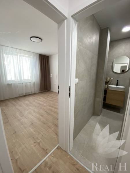 Ein Zimmer mit Holzboden neben dem Badezimmer in einer Zweizimmerwohnung.