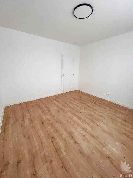 Ein leerer Raum mit hellen Wänden und einem Boden in Holzoptik, 3-Zimmer-Wohnung.