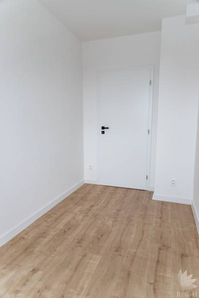 Ein Zimmer in einer 3-Zimmer-Wohnung mit weißen Wänden und einem Boden in Holzoptik.