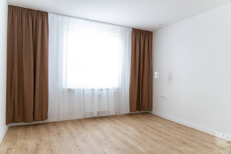 Ein Zimmer in einer 3-Zimmer-Wohnung mit braunen Vorhängen und einem Boden in Holzoptik.
