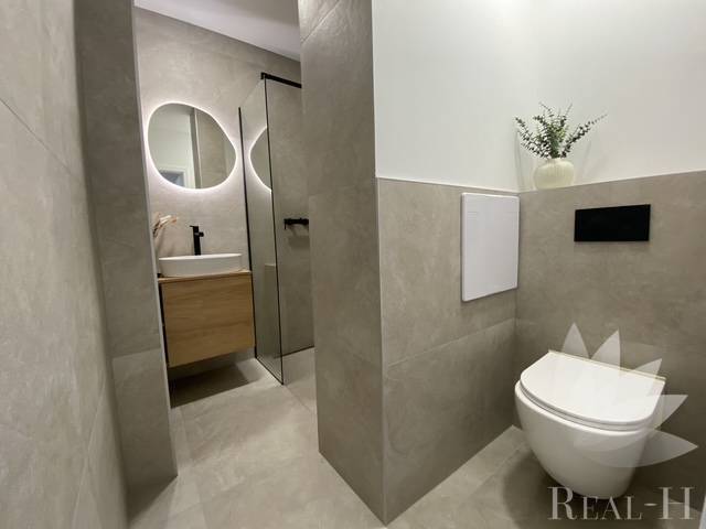 Badezimmer in einer 2-Zimmer-Wohnung mit Toilette, Waschbecken und Spiegel.