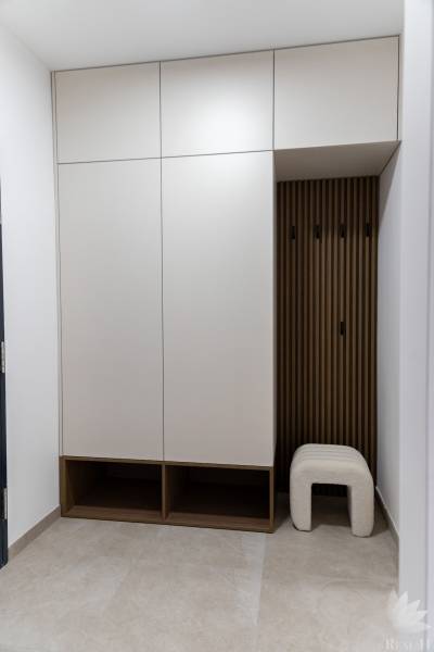 Ein eingebauter weißer Schrank mit offenen Regalen und einem Stuhl in einer 2-Zimmer-Wohnung.