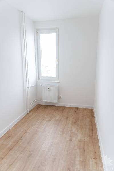 Ein Zimmer in einer 3-Zimmer-Wohnung mit einem Fenster und einem Boden in Holzoptik.