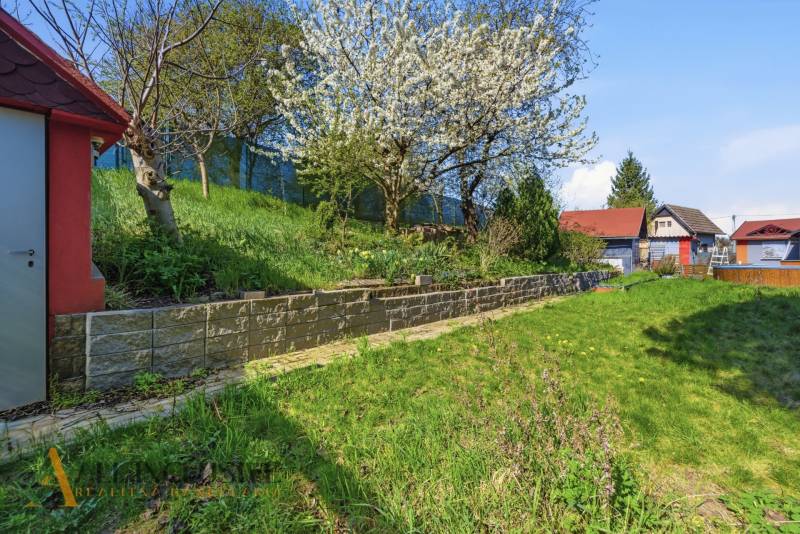Gärten in Kráľová nad Váhom mit blühendem Baum und Grün auf dem Hang.