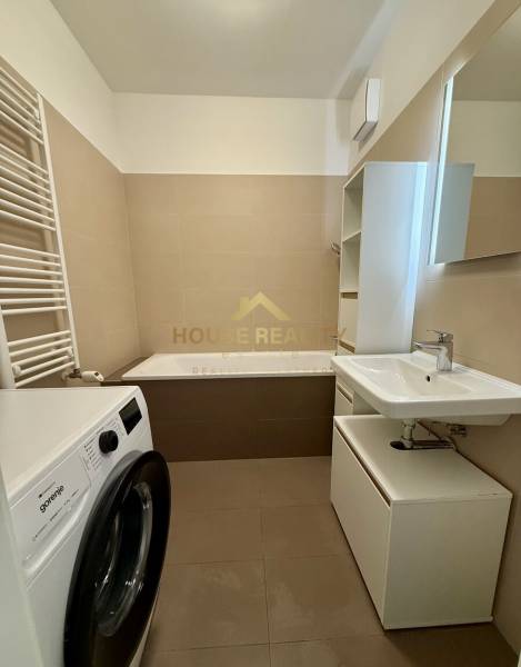 Badezimmer mit Waschmaschine und Badewanne in einer 2-Zimmer-Wohnung, neutrale Farbtöne.