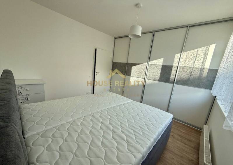 Schlafzimmer mit Bett und Einbauschrank in einer 2-Zimmer-Wohnung, Boden mit Holzdekor.