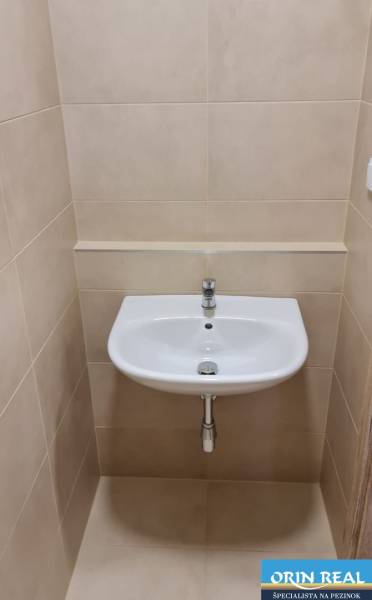Waschbecken im Badezimmer eines Einzimmerapartments mit Fliesen in neutralen Tönen.