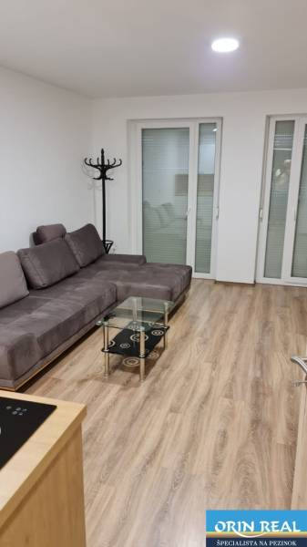 Einzimmerwohnung mit einem bequemen Sofa, einem Glastisch und einem Boden in Holzoptik.
