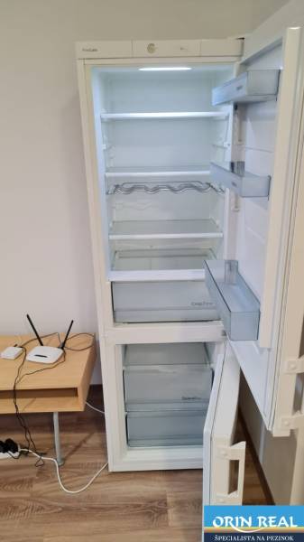 Otváracia Kühlschrank in einem Studio-Apartment mit Holzboden und kleinem Tisch.