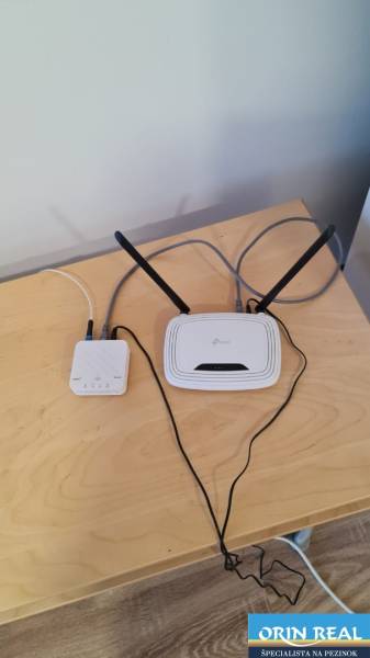Ein Tisch mit einem Netzwerkgerät und einem Router in einem Studio-Apartment, Boden mit Holzdekor.