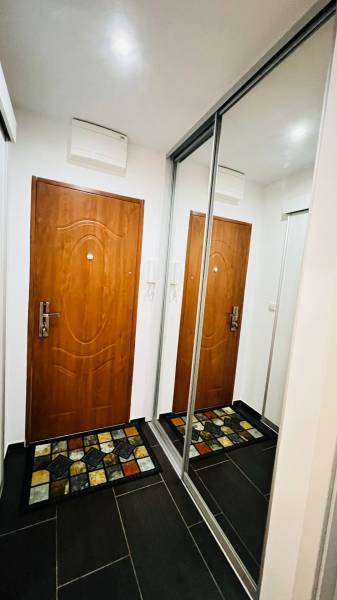 Flur in einer 3-Zimmer-Wohnung mit Türen, einem Spiegelschrank und einem bunten Teppich.