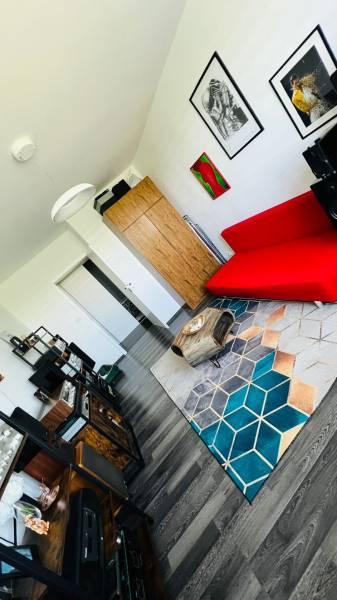 Wohnzimmer in einer 3-Zimmer-Wohnung mit einem roten Sofa und einem Boden in Holzoptik.