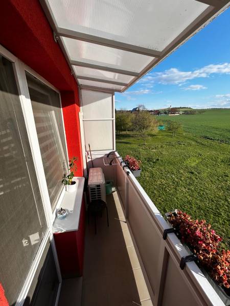 Der Balkon einer 3-Zimmer-Wohnung in Gbeľoch mit Blick auf grüne Wiesen und Blumen.