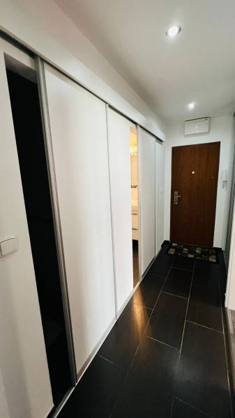 Flur in einer 3-Zimmer-Wohnung mit Schiebetüren und dunkelbraunem Boden.