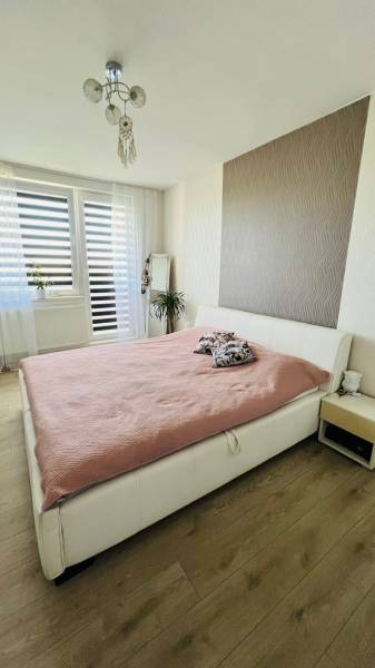 Helles Schlafzimmer mit großem Bett, Spiegel und Holzboden in einer 3-Zimmer-Wohnung.