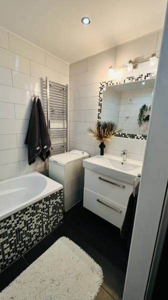 Elegantes Badezimmer mit Fliesen, Waschbecken und Badewanne, Teil einer 3-Zimmer-Wohnung.