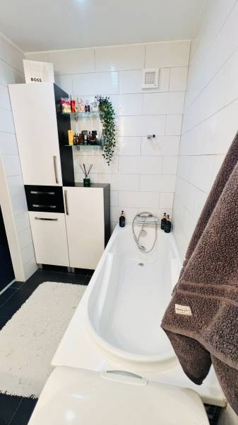 Badezimmer mit Badewanne, Schränken und Dekorationen in einer 3-Zimmer-Wohnung.