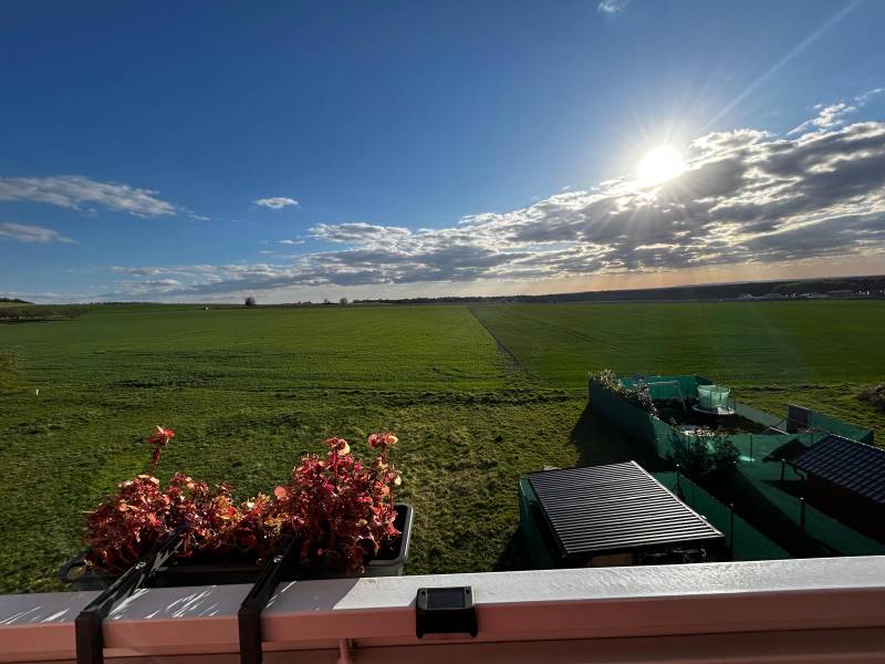 Ein Blick auf die weite grüne Landschaft und einen Balkon mit Blumen in Gbely.