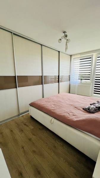 Schlafzimmer mit Einbauschrank, Holzboden und großem Fenster in einer 3-Zimmer-Wohnung.