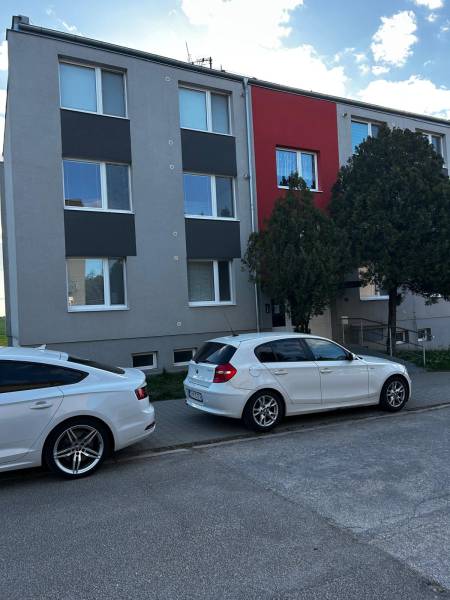Ein Wohnhaus in Gbely mit moderner Fassade und geparkten Autos vor einer 3-Zimmer-Wohnung.