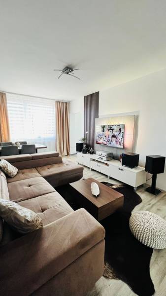 Wohnzimmer mit Ecksofa, TV-Schrank und Boden mit Holzdekor.